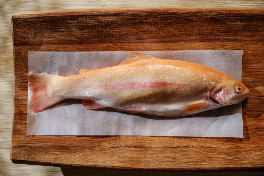 Frischer Fisch auf einem Holzbrett, kurz vor der Zubereitung.